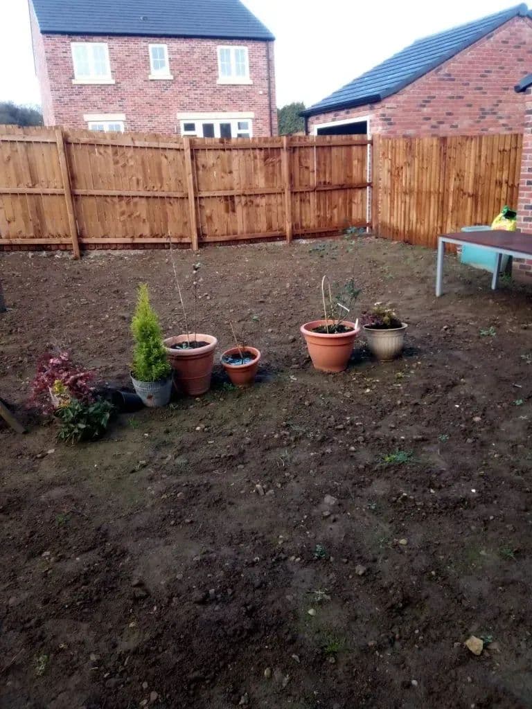 The garden before work: bare soil, a new close-board fence and a few pots along the boundary