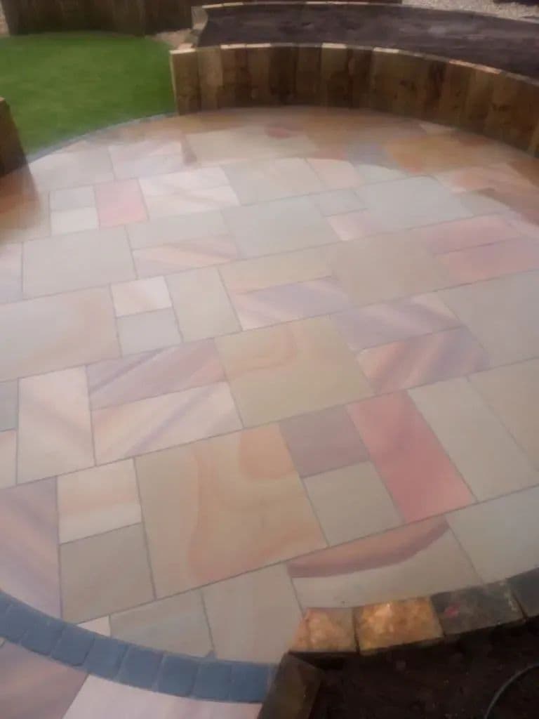 Premiastone Maple flags curving round to meet the lawn, with a band of dark setts set into the paving