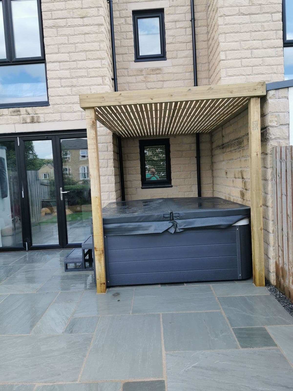The hot tub set under the slatted timber pergola on Kandla grey paving