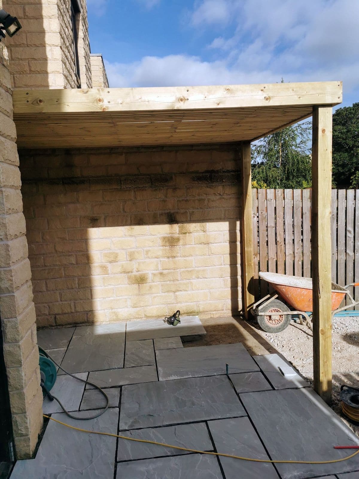 The timber pergola frame going up over the new paving part-way through the build
