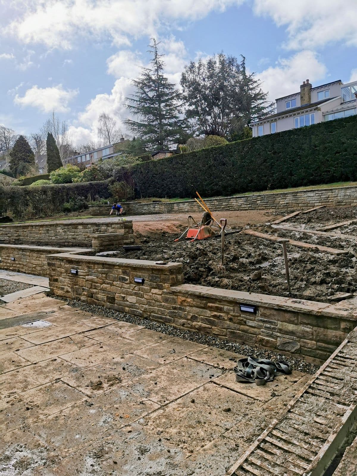 The stone retaining walls built and the ground still bare, part-way through the build