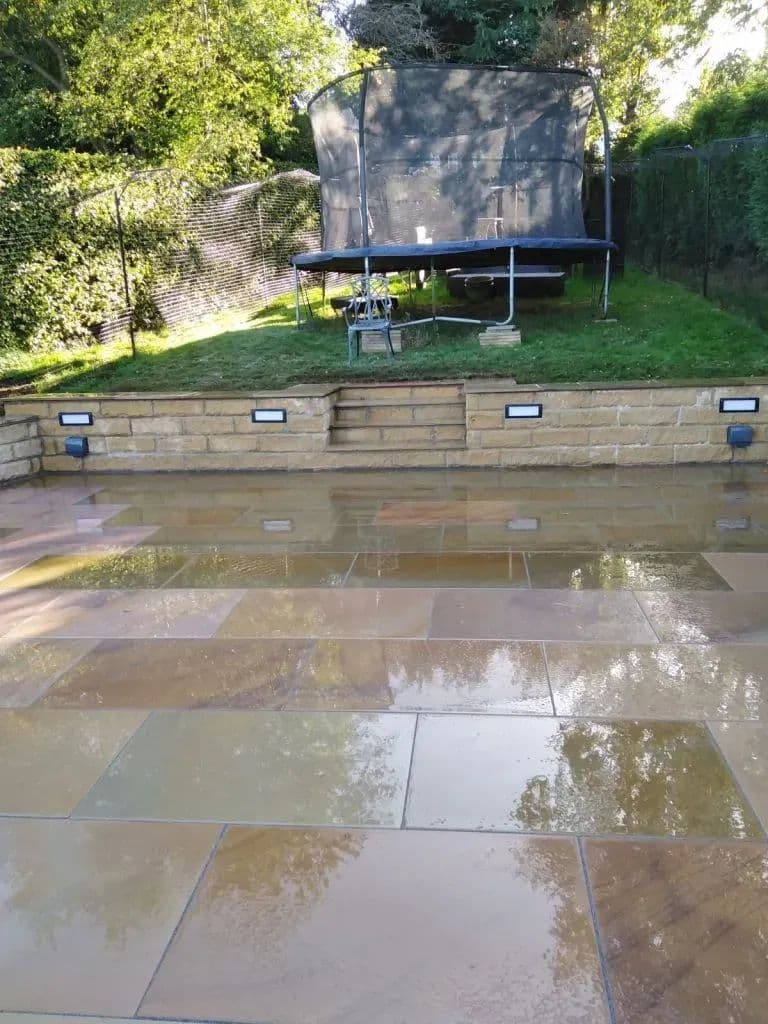 The finished Maple-paved patio with lights set into the retaining wall behind it