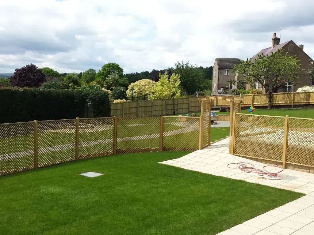 New close-board and trellis fencing along the boundary, with the level lawn and paving inside it