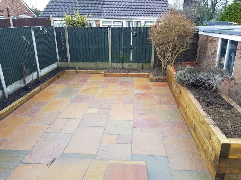 The paved area with sleeper planters along both boundaries and shrubs planted through them