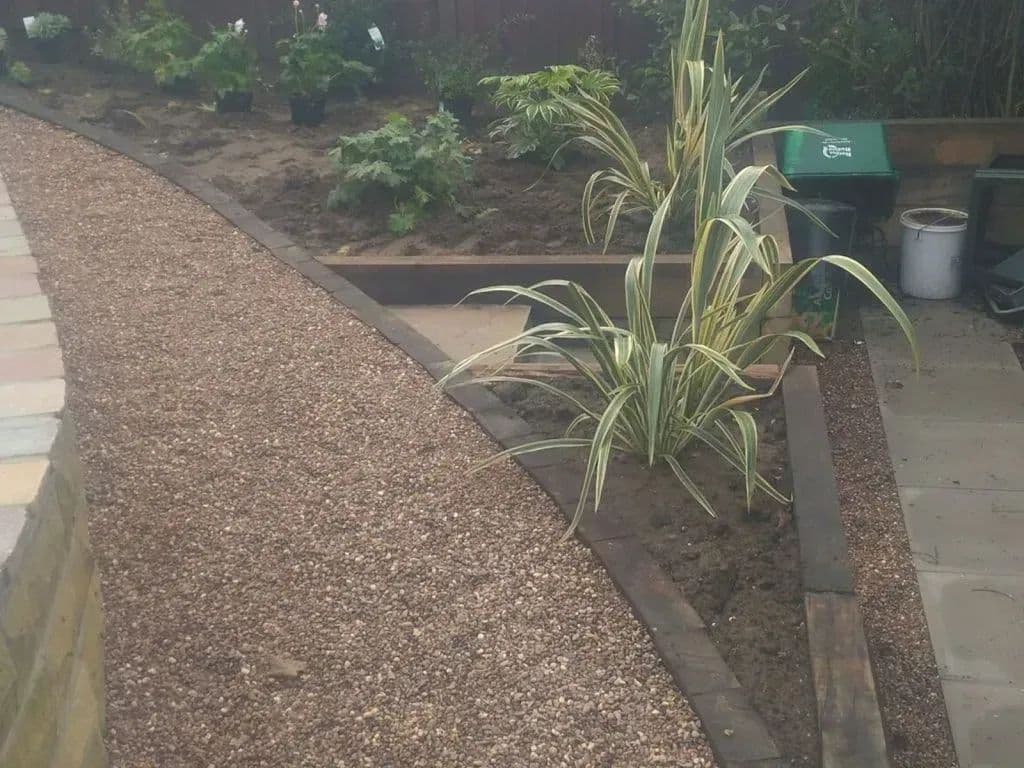 The gravel path running past a wide planting bed edged with timber
