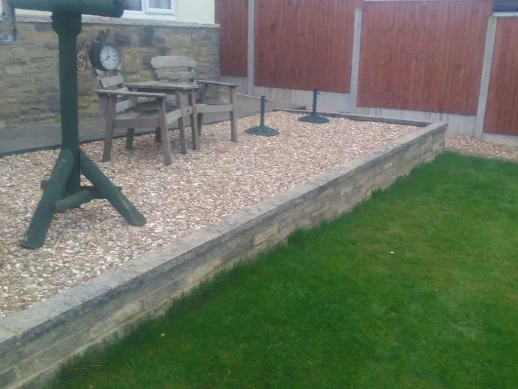 The stabilised gravel path running between the stone walling and the lawn, with a seating area at the top