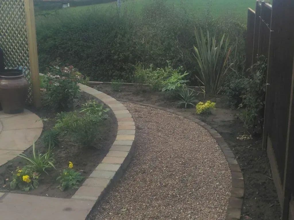 New planting between the path and the fence, with the gravel path curving round