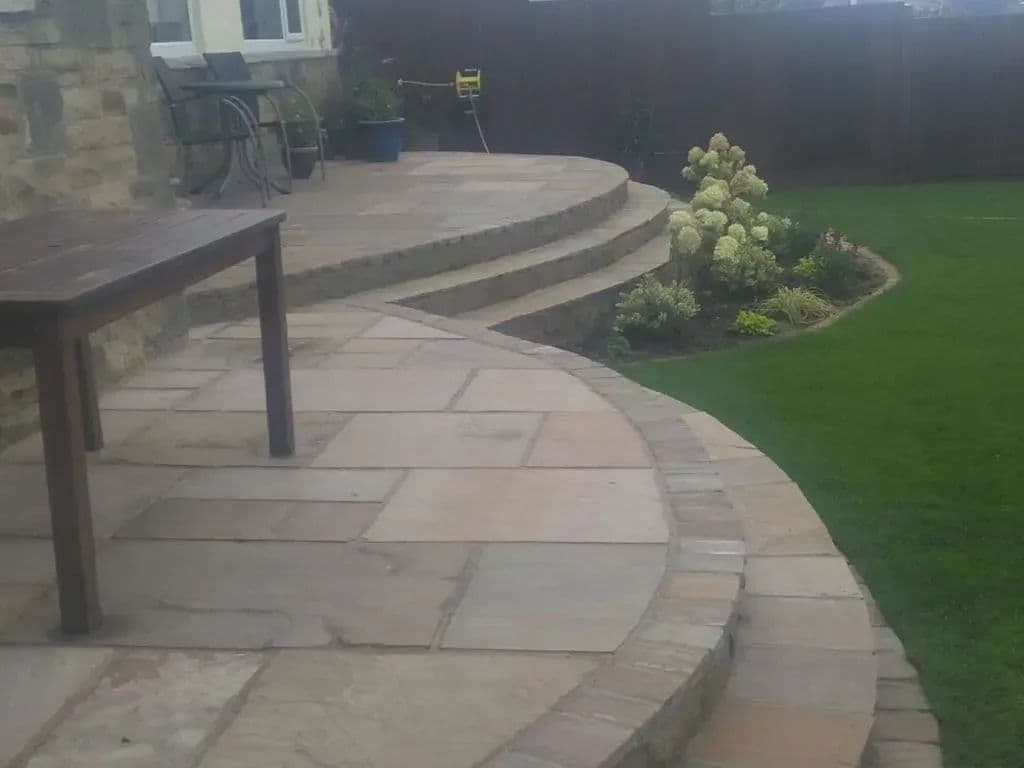The semi-circular patio with curved steps up to the house and planting either side