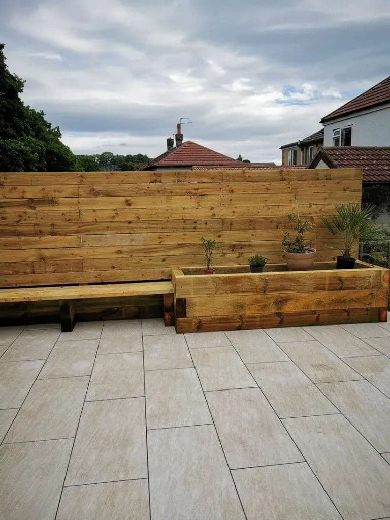 The porcelain patio with timber planters along the boundary and the boarded screen behind