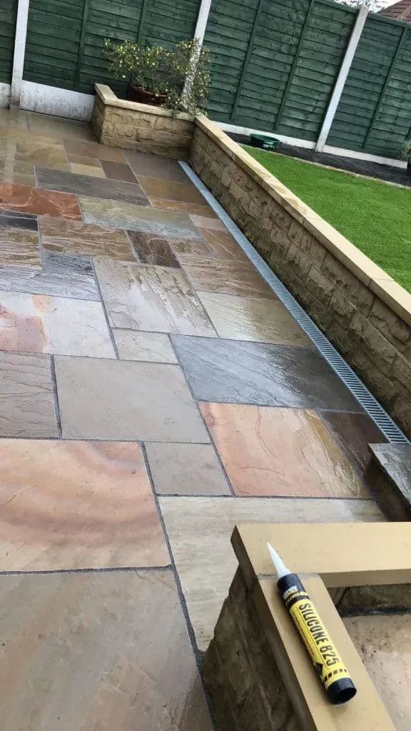 The paved area with the retaining wall separating it from the lawn above