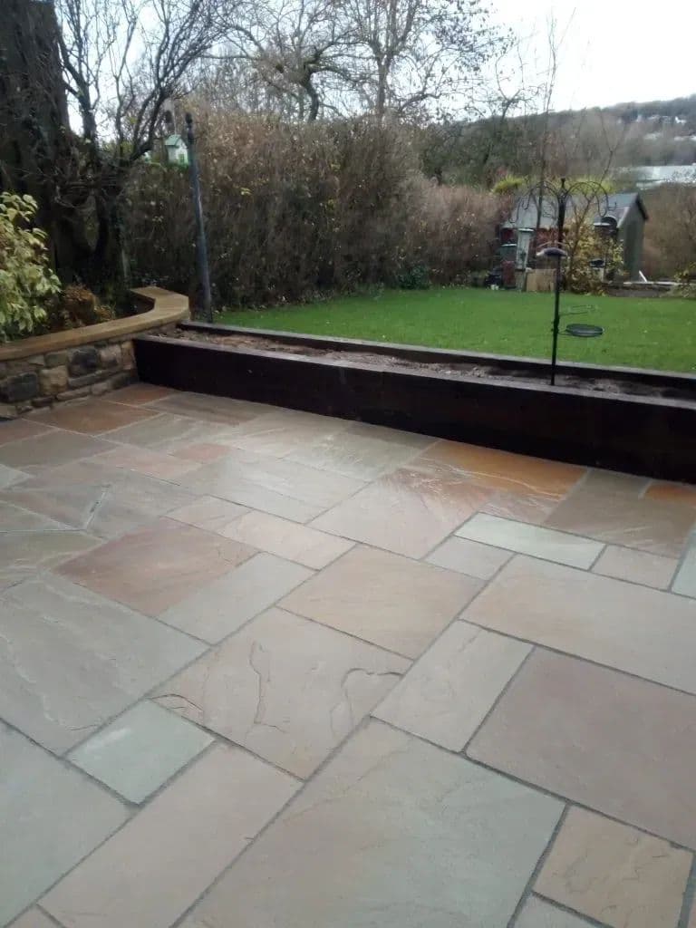 The paved area meeting the lawn, with a timber-edged raised bed along the boundary