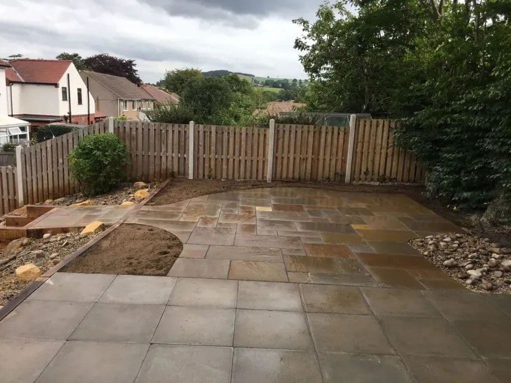 The finished patio running to the boundary fence, with sleeper edging and gravel alongside