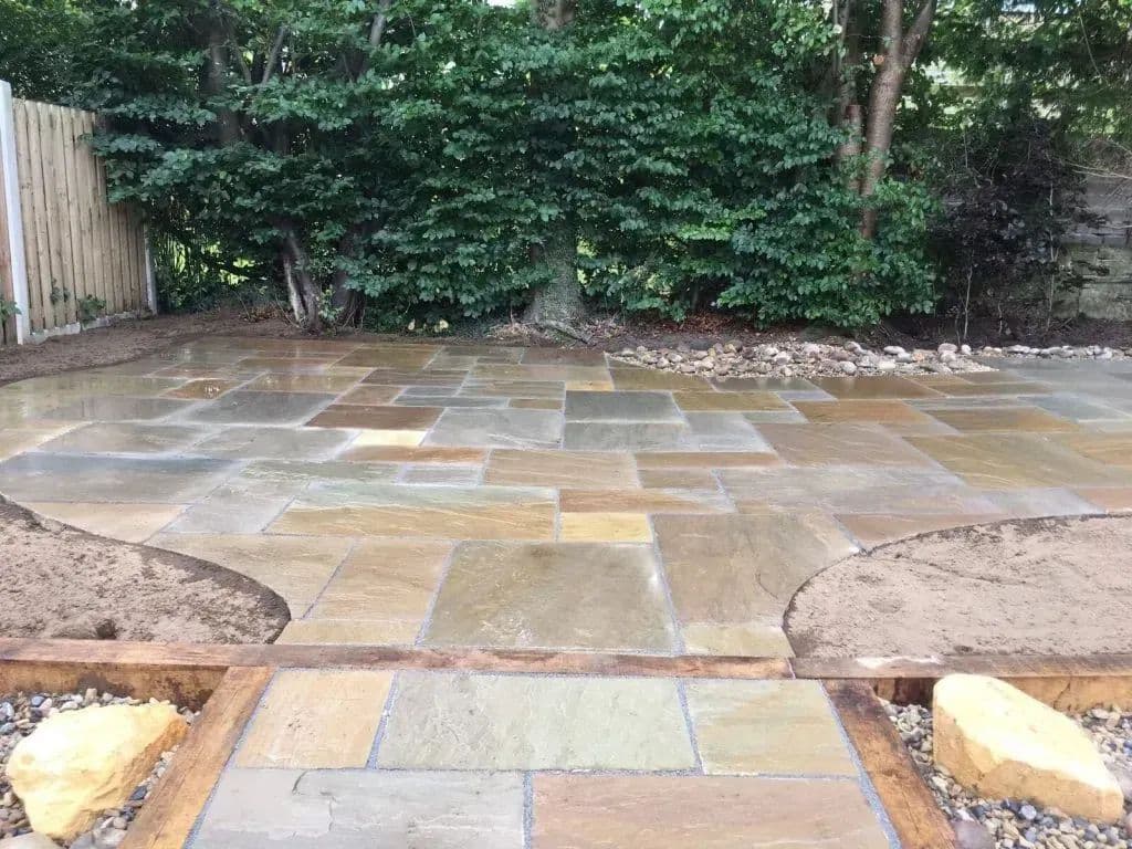 The paved patio at the rear of the garden with the rockery bank behind it