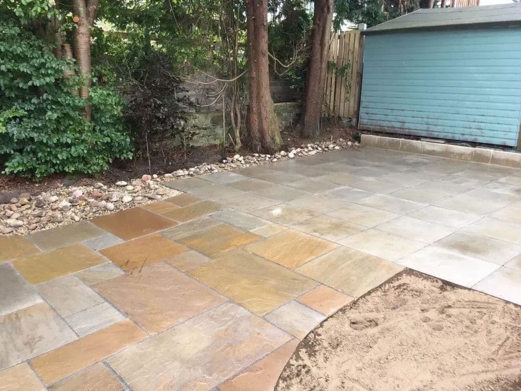 The patio from the corner, with cobbles along the edge and the shed behind