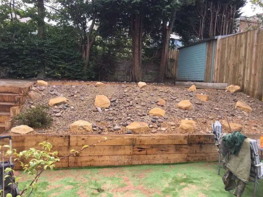 The rockery section above the sleeper retaining wall, with the patio below it