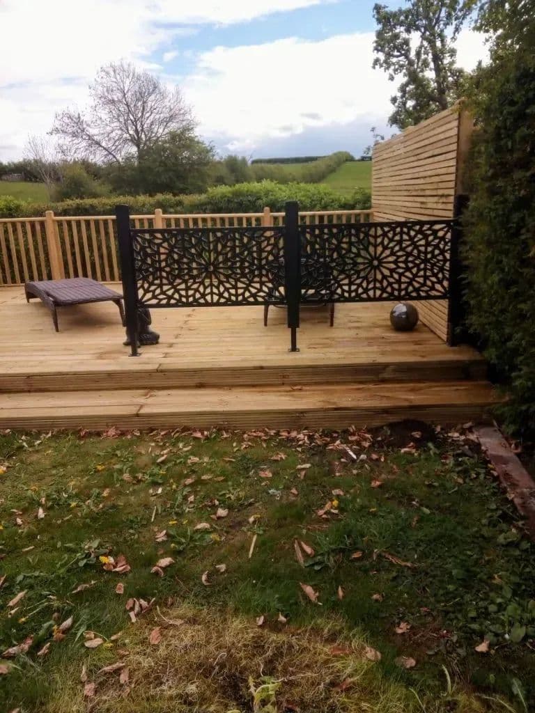 The deck with its metal screen panels, seen from across the lawn