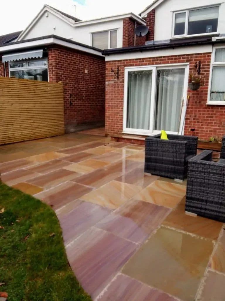 The sandstone patio outside the back doors, with seating on it and the lawn beyond