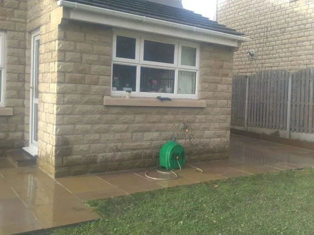 The paving turning the corner of the house, with the lawn alongside it