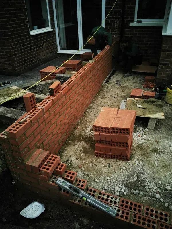 The brick retaining wall going up along the side of the house during the build
