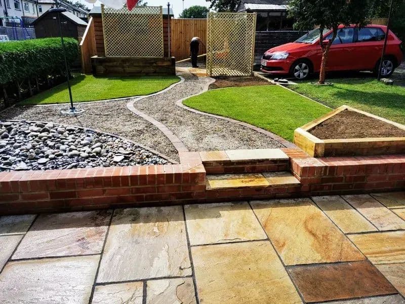 The finished garden from the patio: lawn, gravel, brick edging and the trellis by the drive