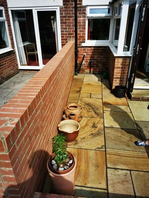 Sandstone paving running alongside the new brick wall at the back of the house