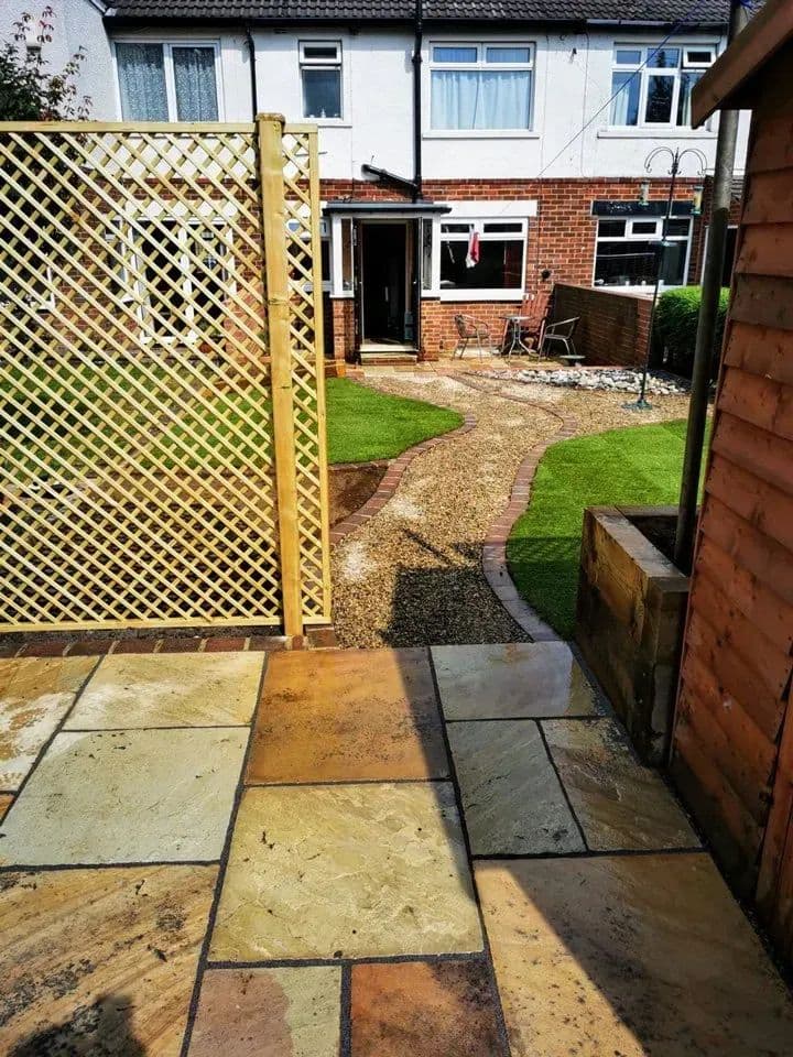 The trellis screen beside the path, with the lawn and the house behind