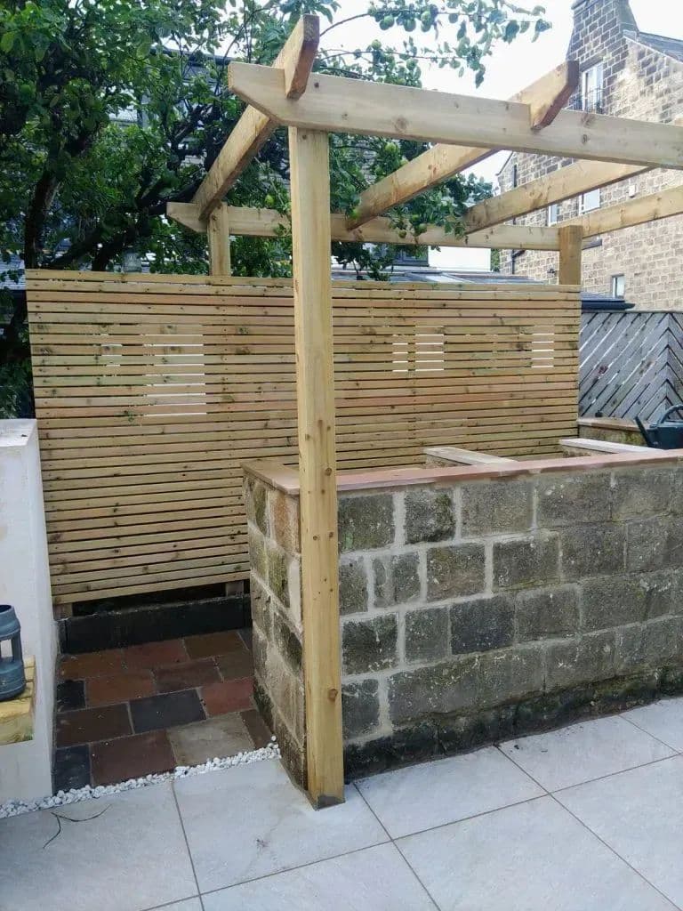 The timber pergola and slatted screen built above the rendered wall