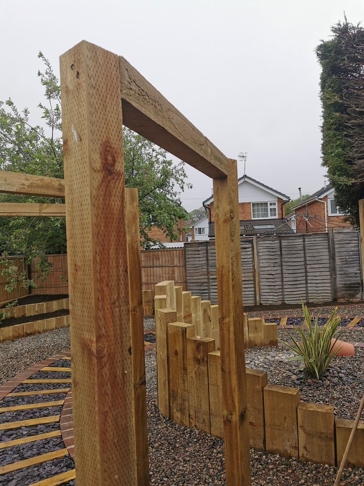 Timber sleeper uprights beside the gravel path, with slate setts leading through