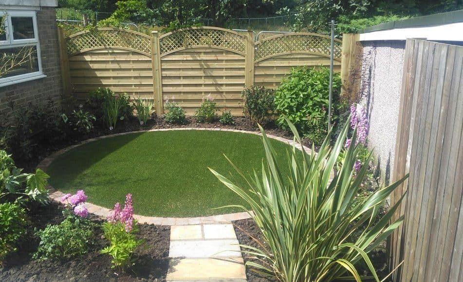 An oval lawn edged in brick, with borders of foxgloves and shrubs